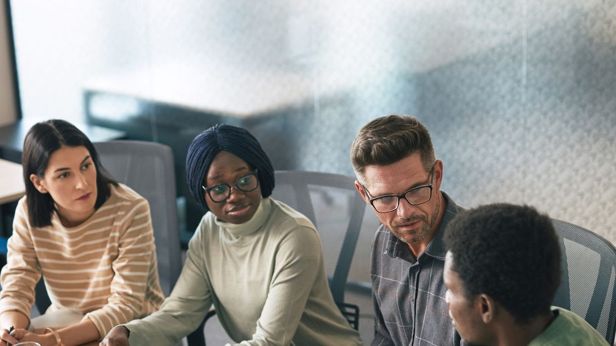 A diverse team of professionals discussing employee health benefits in a modern office