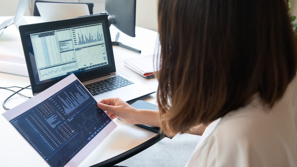 A professional reviewing benefits data and financial charts on a laptop