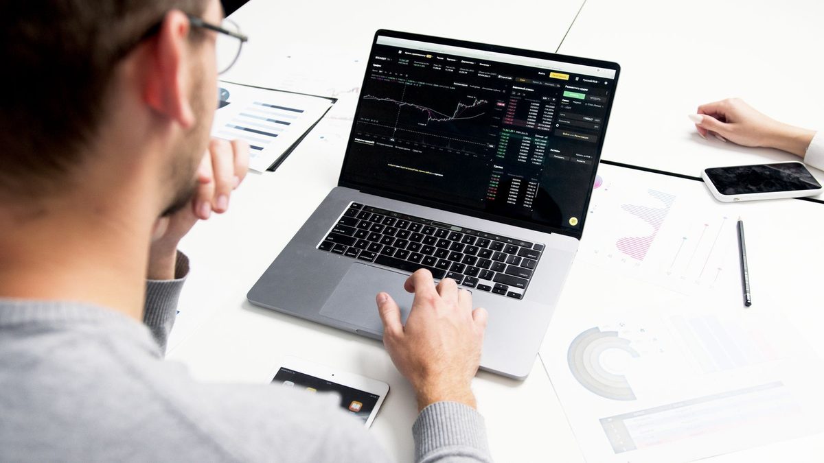 A professional reviewing benefits data and financial charts on a laptop