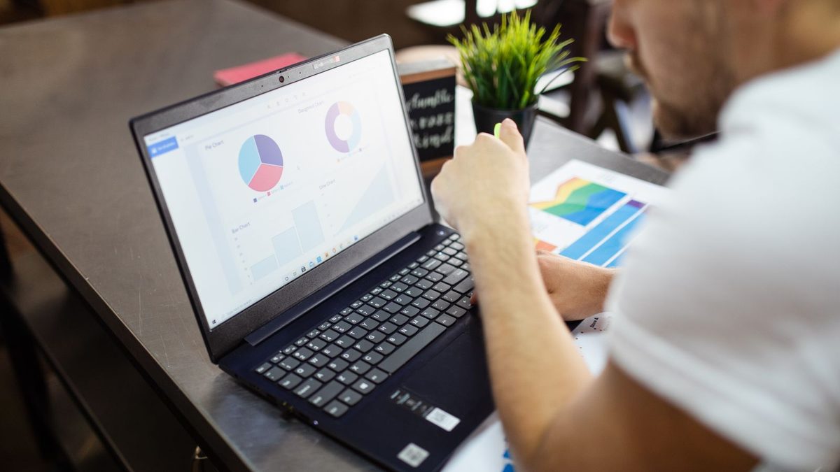 A professional reviewing benefits data and financial charts on a laptop