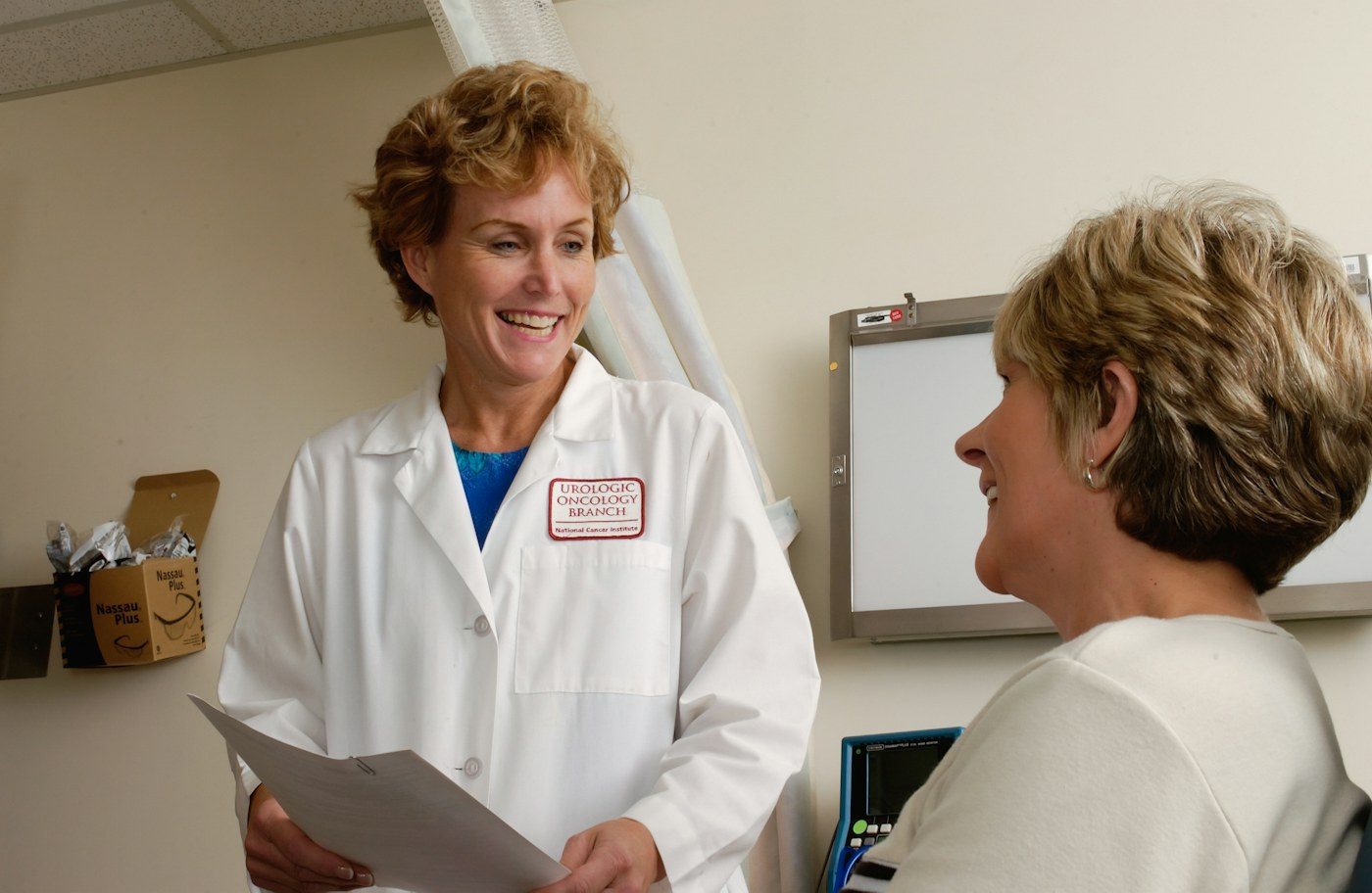 A doctor in a white coat talks with a smiling patient during an appointment
