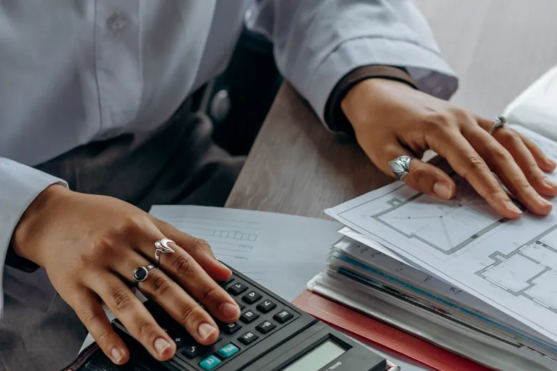 Person comparing health insurance renewal figures with a calculator and paperwork