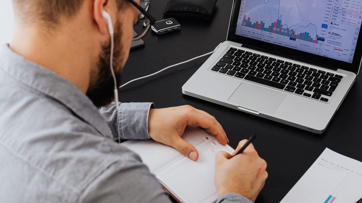 A professional reviewing benefits data and financial charts on a laptop