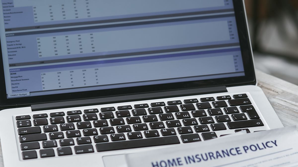 Insurance policy documents beside a laptop displaying financial charts